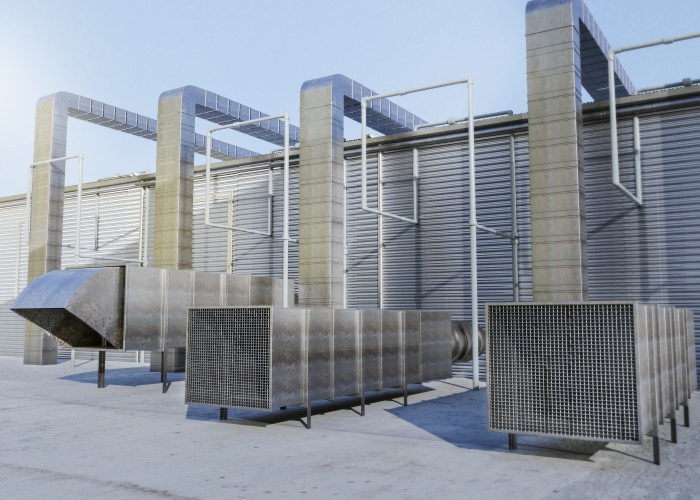 Industrial ventilation and cooling system with large air ducts and HVAC units installed outside a commercial building.