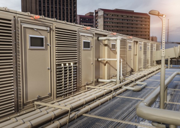 Rooftop ventilation units with metal ducts and grilles on a commercial building