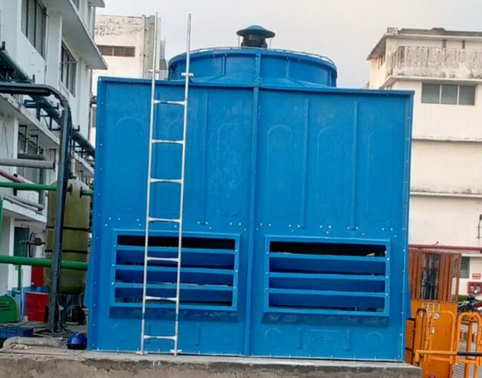 Blue industrial FRP cooling tower with a ladder and ventilation openings.