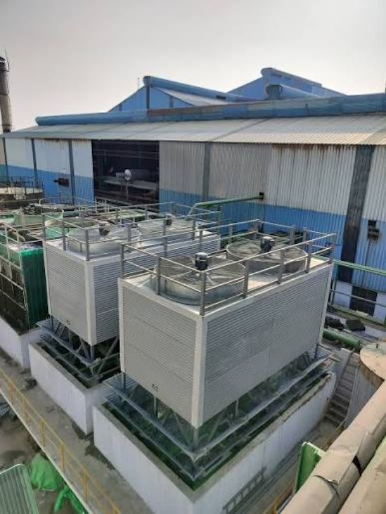 Pultruded FRP cooling towers installed on the rooftop of an industrial facility, with multiple rectangular units, metal railings, and connected piping.
