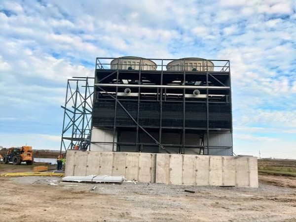 Pultruded FRP Cooling Towers installed at an industrial facility with a steel support structure and concrete foundation under a partly cloudy sky.